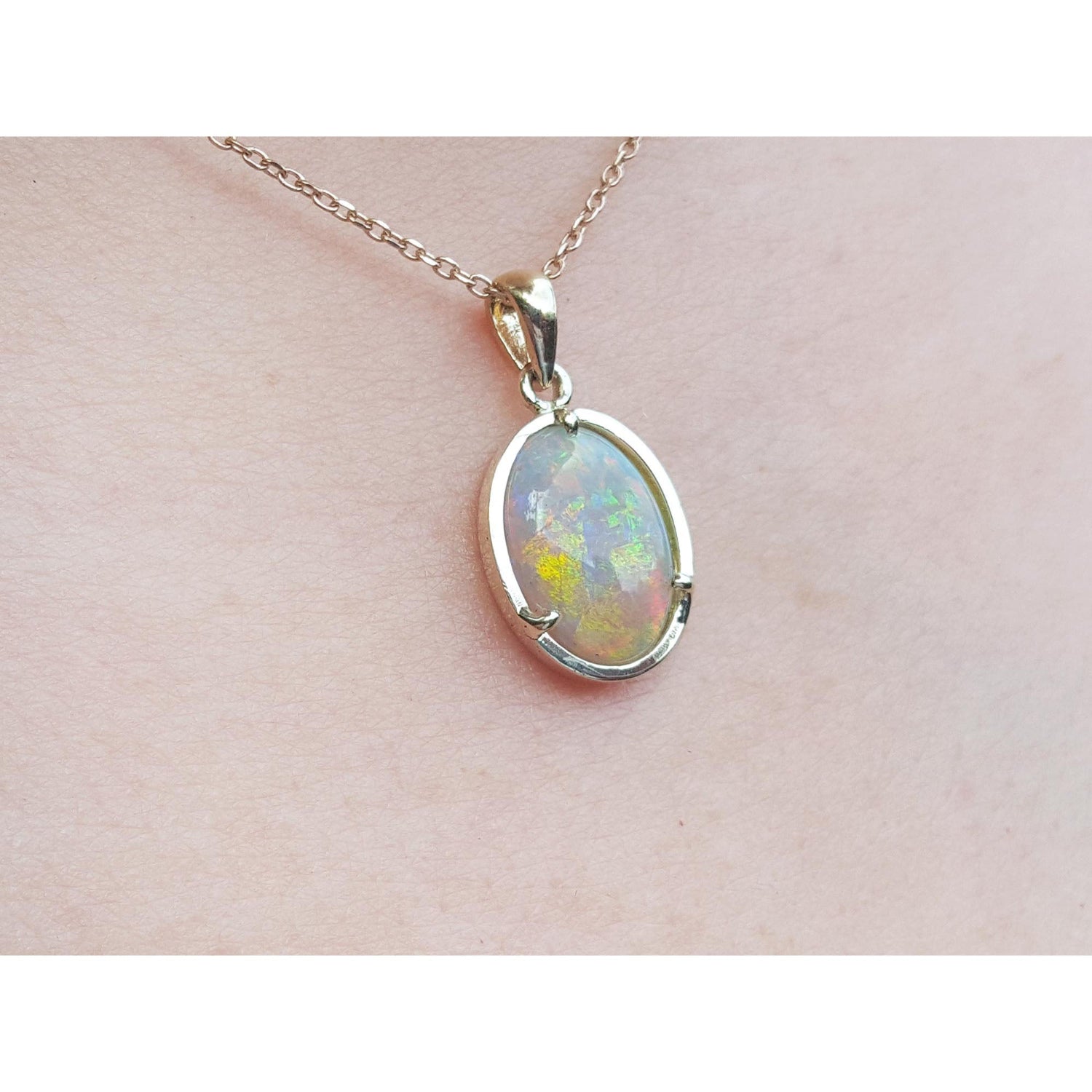 Opal pendant necklace on a light pink skin background.