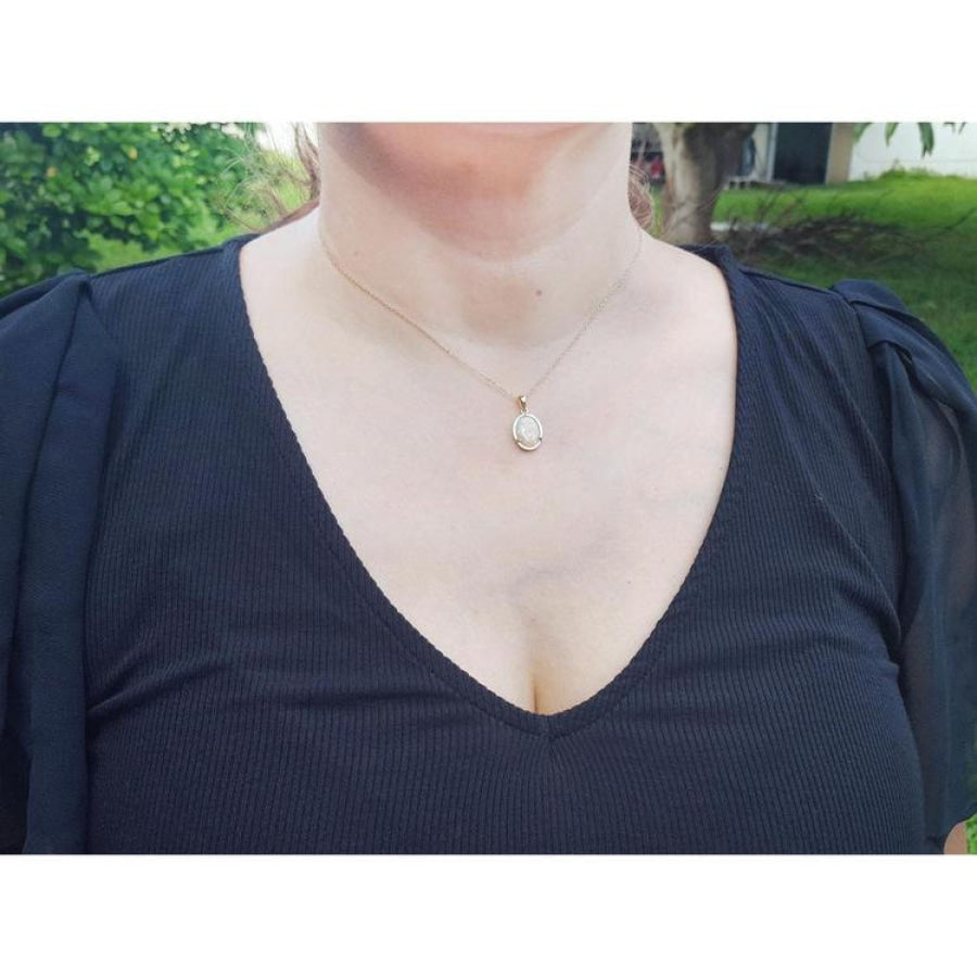 Woman wearing a 14k yellow gold necklace with a solid oval white Australian opal pendant.