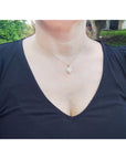 A woman wearing a black top with a natural opal necklace, outdoors.
