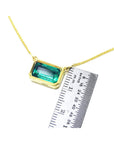 East-west emerald-cut solitaire emerald necklace in 18K yellow gold, shown with a ruler for scale.