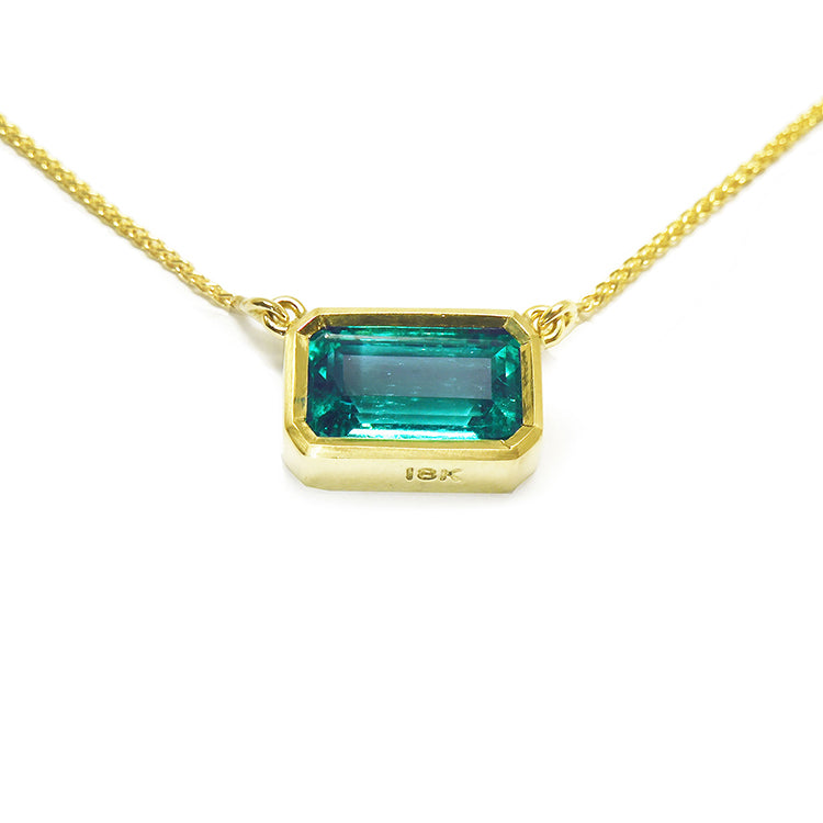 Emerald-cut emerald solitaire women's necklace east-west orientation handcrafted in 18k yellow gold