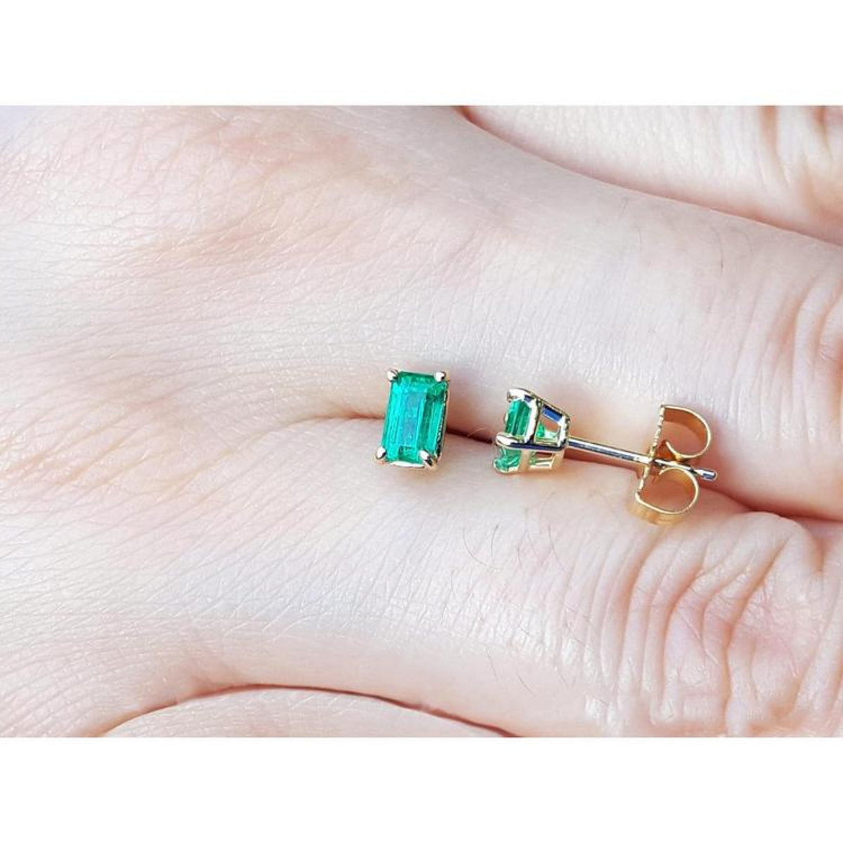 Emerald cut emerald stud earrings, 0.78 ct, in 14K yellow gold basket settings with push backs.
