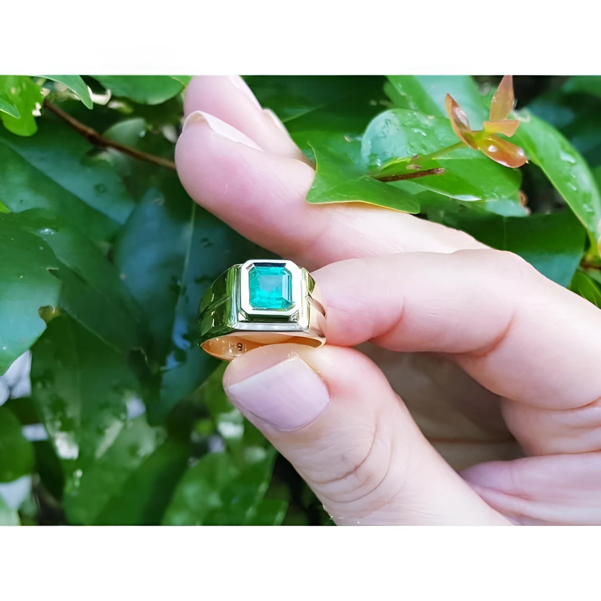 Hand holding a 1.53 ct. square emerald solitaire ring in an 18K yellow gold bezel setting.
