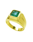 Gold ring with a bezel set emerald stone on a white background