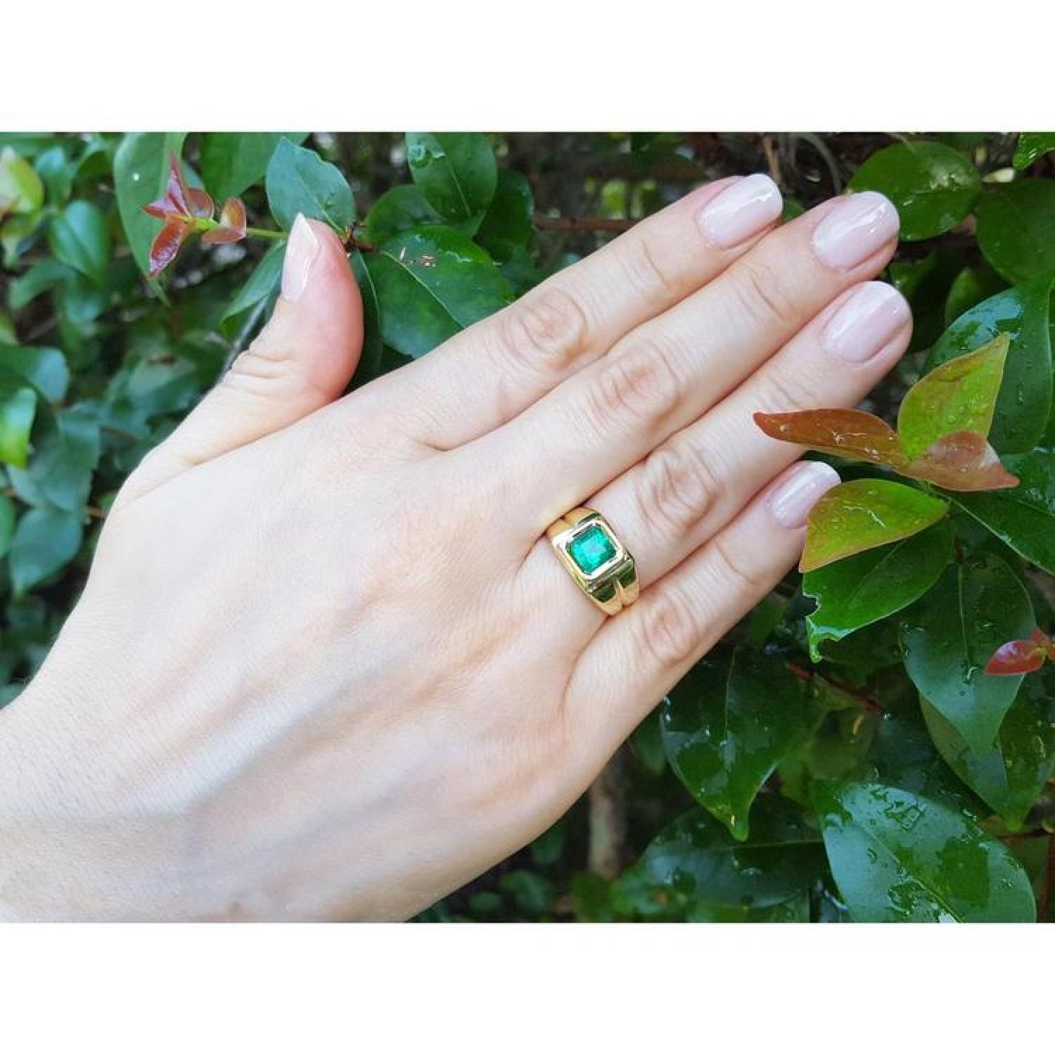 1.53 ct. square emerald solitaire ring in 18K yellow gold with a bezel setting on a hand.
