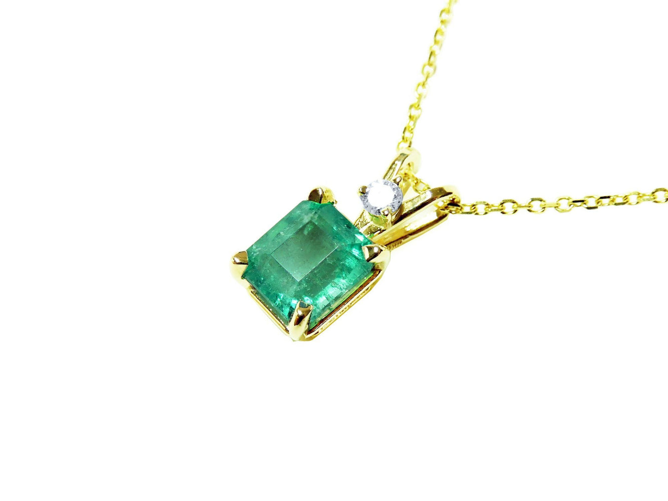 Gold necklace with a natural colombian emerald pendant on a left-side position topside view.