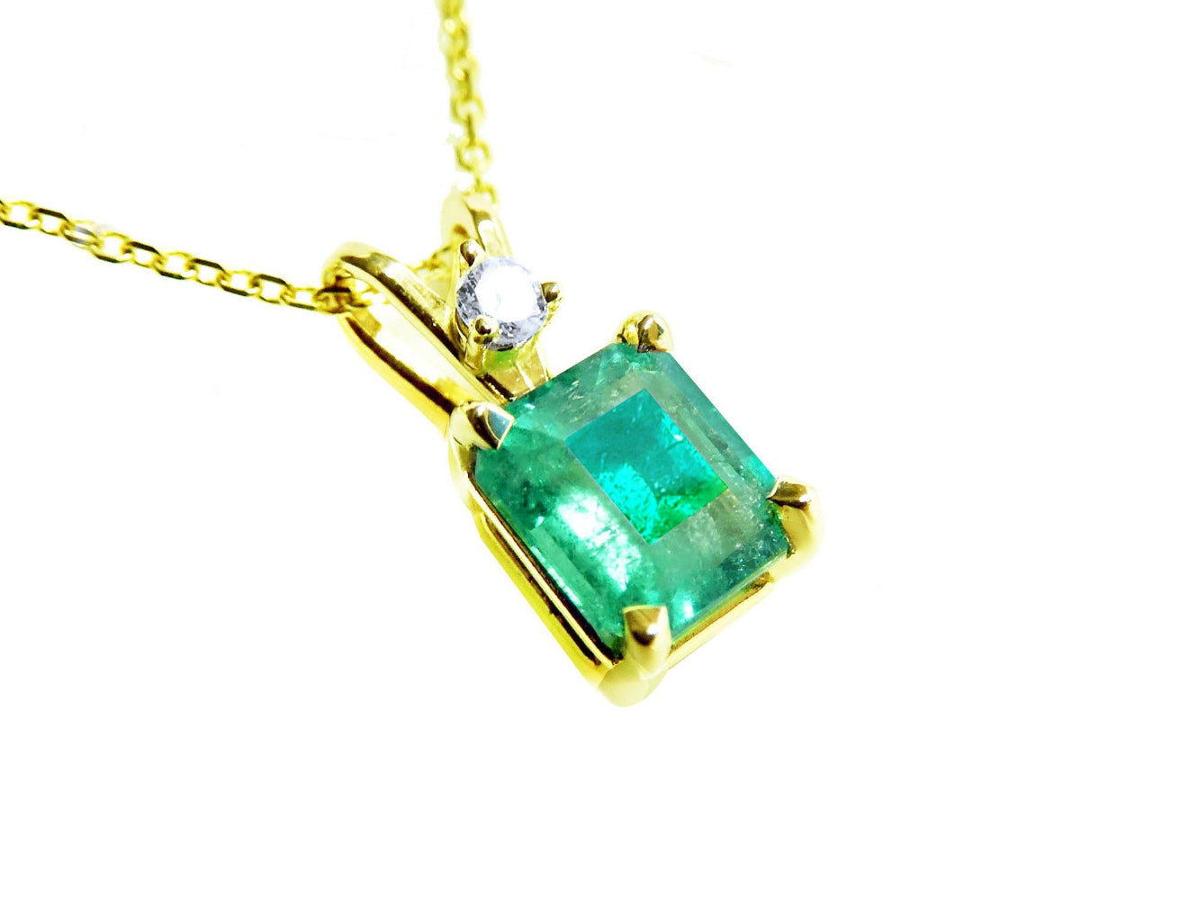 A yellow gold pendant with an emerald-cut natural colombian emerald displaying the topside.