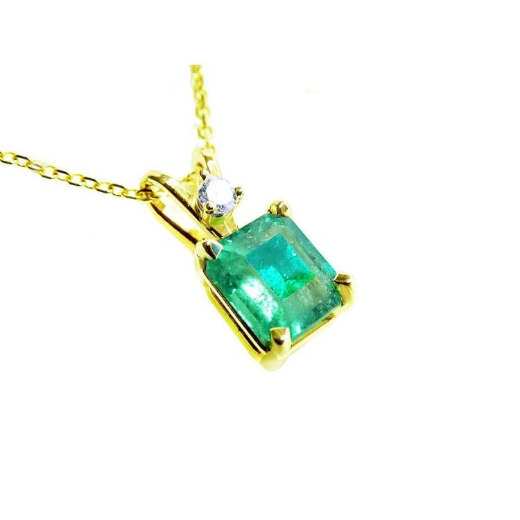 A yellow gold pendant with an emerald-cut natural colombian emerald displaying the topside.