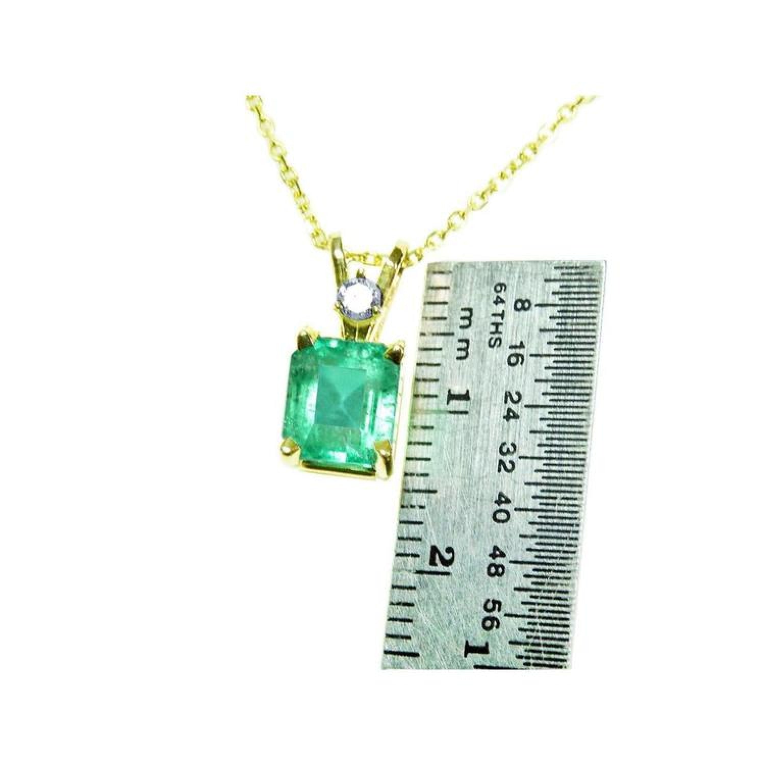 Emerald-cut emerald pendant in 14K yellow gold with diamond accent, shown next to a ruler.