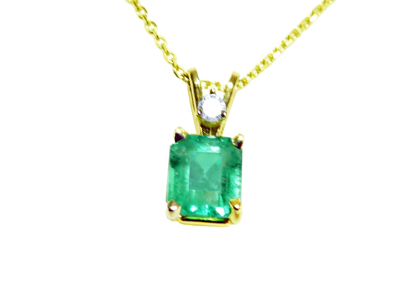 This natural emerald-cut colombian emerald pendant made of yellow gold is showing its topside.