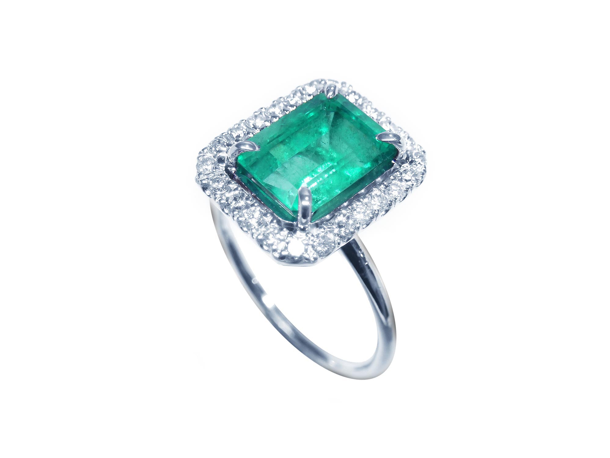 White gold women&#39;s emerald ring with halo diamond on a topside profile view.