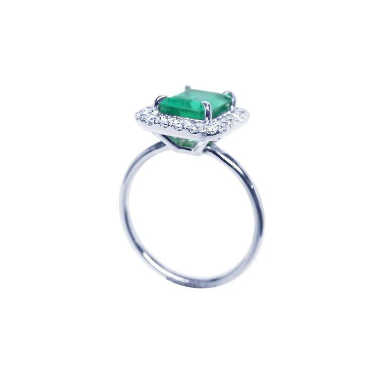 Emerald-cut emerald ring with halo diamonds in 14K white gold.