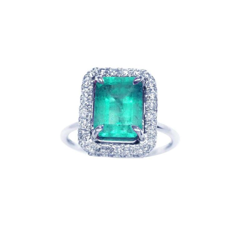 A square emerald-cut emerald ring for women encircled by a halo diamond in 18k white gold.