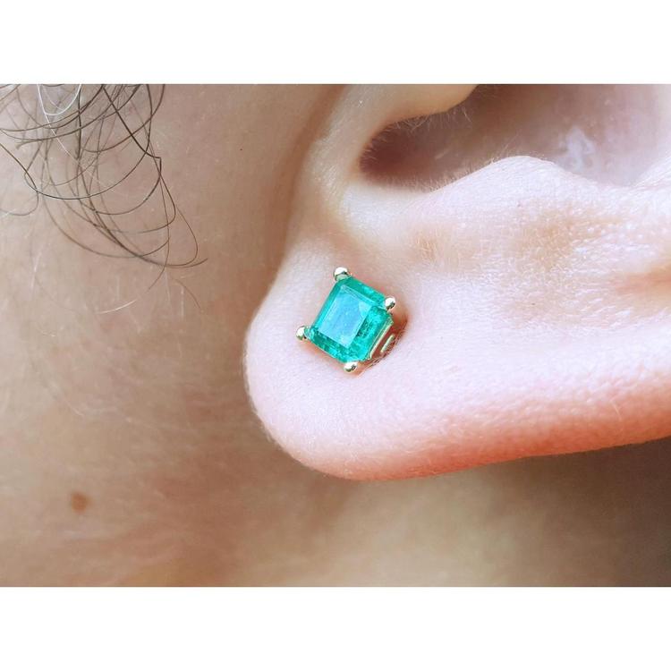 14k yellow gold square natural colombian emerald stud earring on an earlobe.