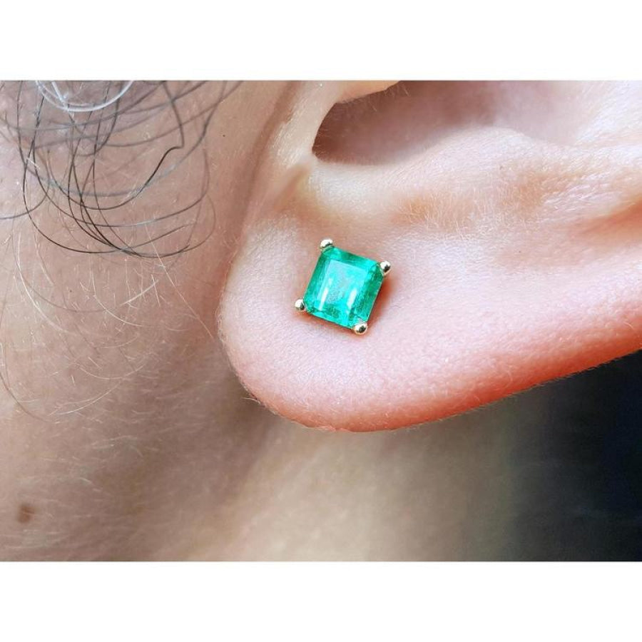Square emerald stud earring in 14K yellow gold, worn on an ear.