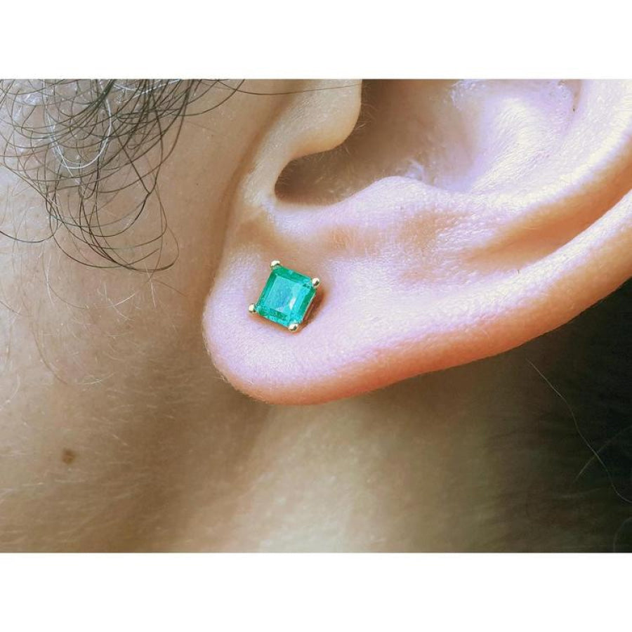 Square emerald stud earring in 14K yellow gold, worn on an ear.