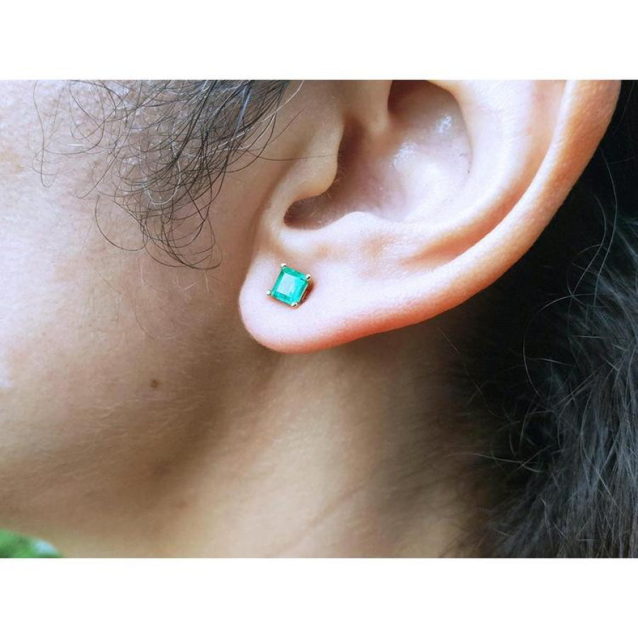 Square emerald stud earring in 14K yellow gold on an earlobe.