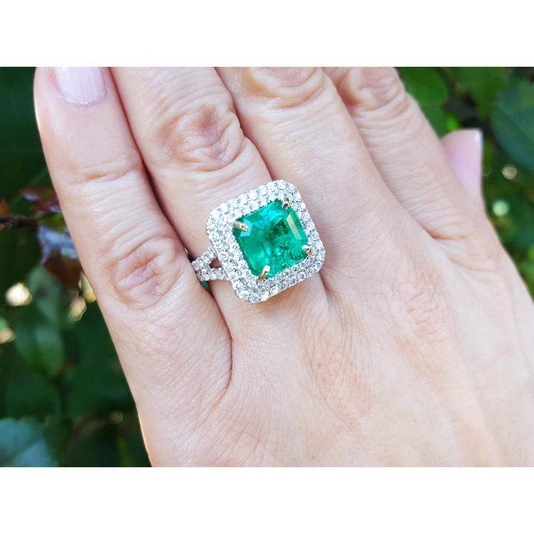 4.14 ct GIA F1 Colombian emerald ring with diamond halo and band in 14K white gold on a hand.