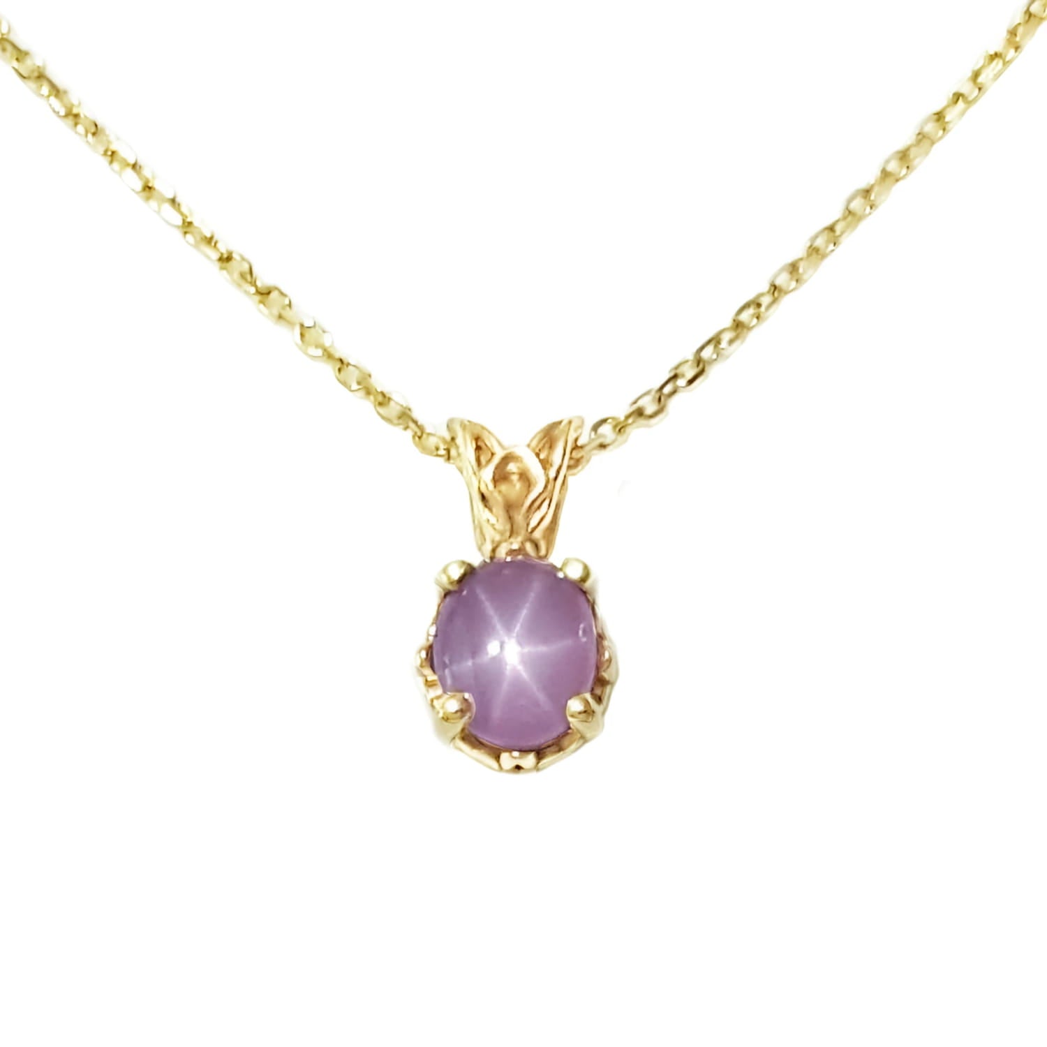 This natural star pink sapphire pendant necklace shows its asterisk under a LED bulb light and it is made of 14kgold.