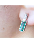 Close-up of a baguette cut emerald stud earring on a person's ear.