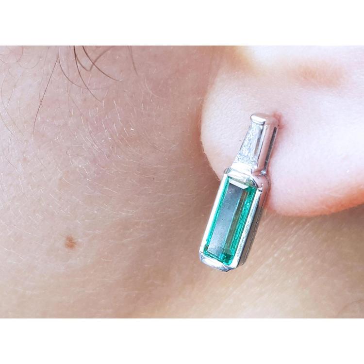 Close-up of a baguette cut emerald stud earring on a person's ear.
