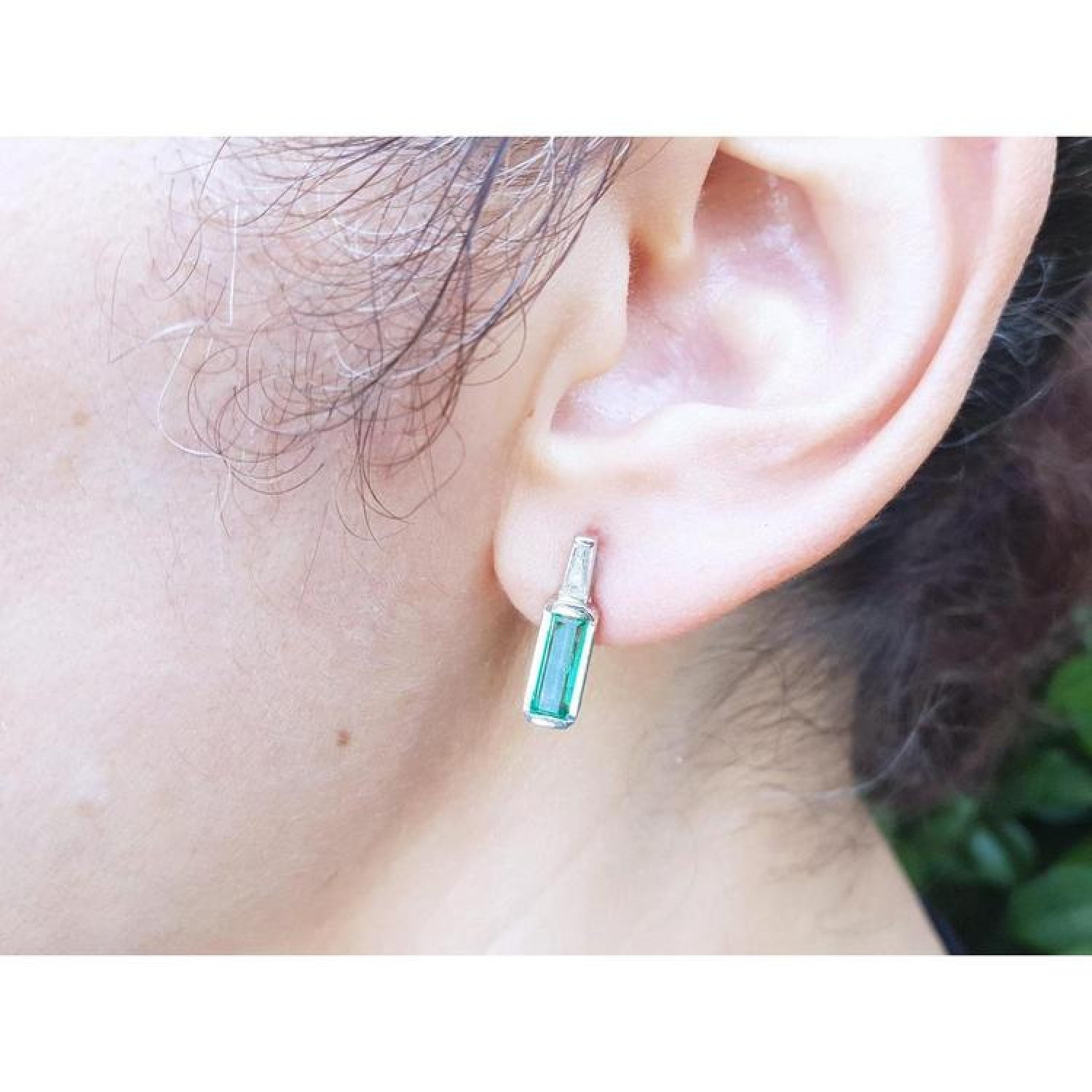 2.00 ct. natural baguette emerald stud earrings in 14k white gold, featuring a medium green emerald and diamond accent.