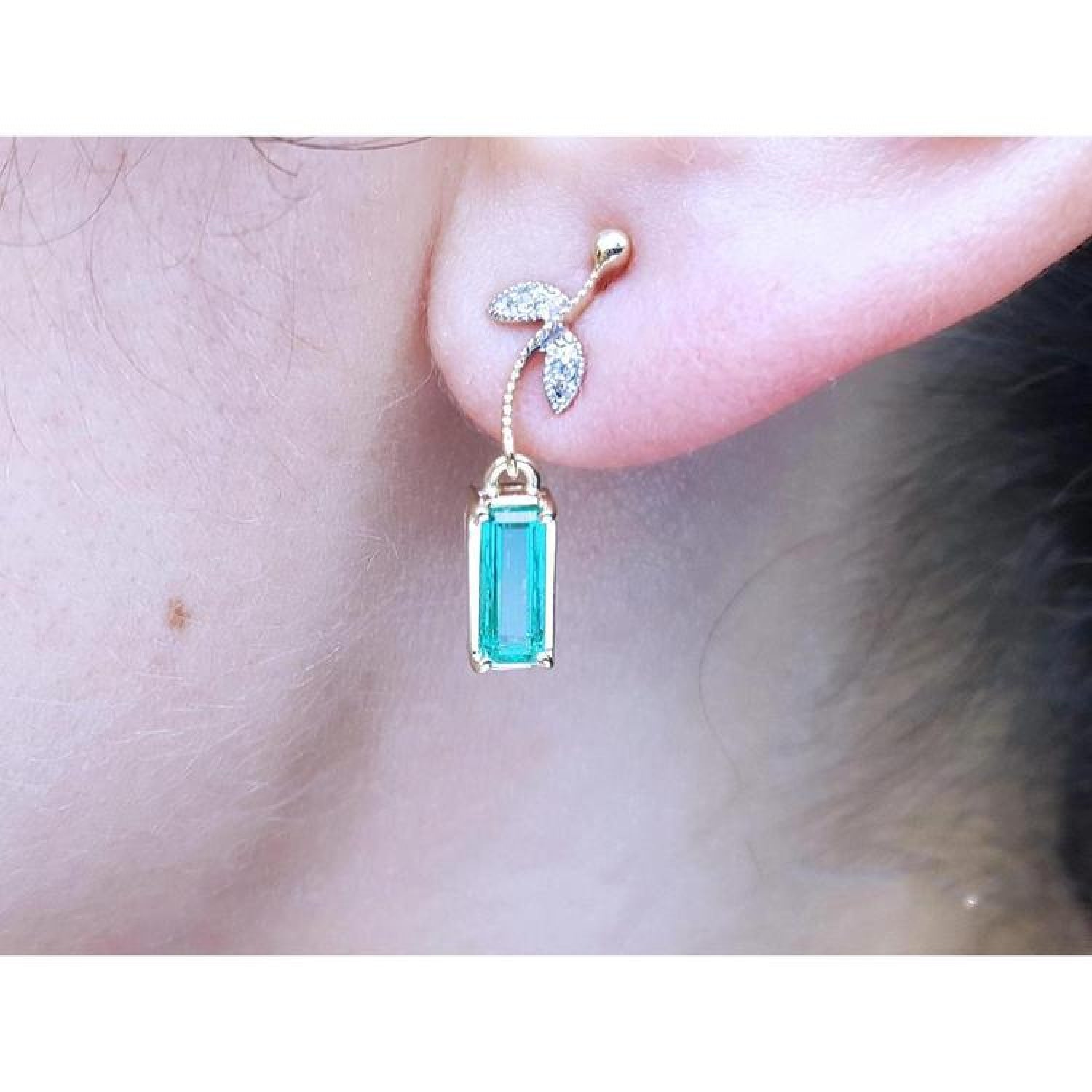 14K gold stud emerald leaf earrings with vibrant green rectangular emeralds and diamond accents.