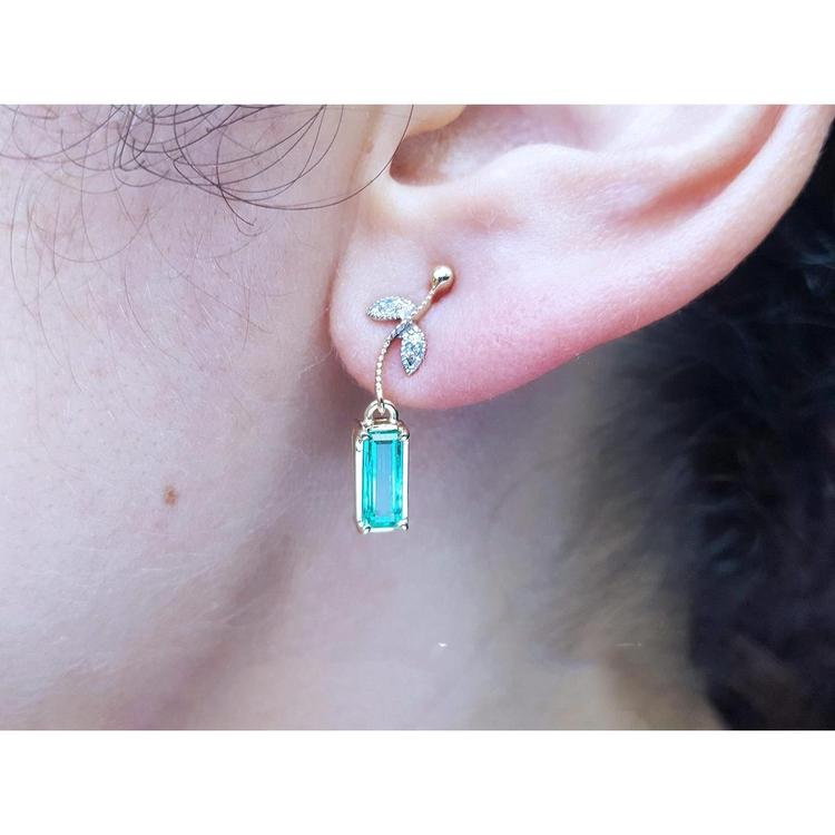Close-up of an ear wearing a 14k yellow gold emerald earring