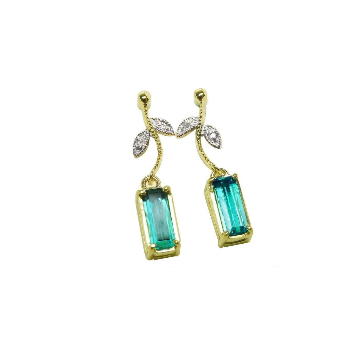 Front position of a pair of emerald dangle earrings in 14k yellow gold, pending from a leafy stem