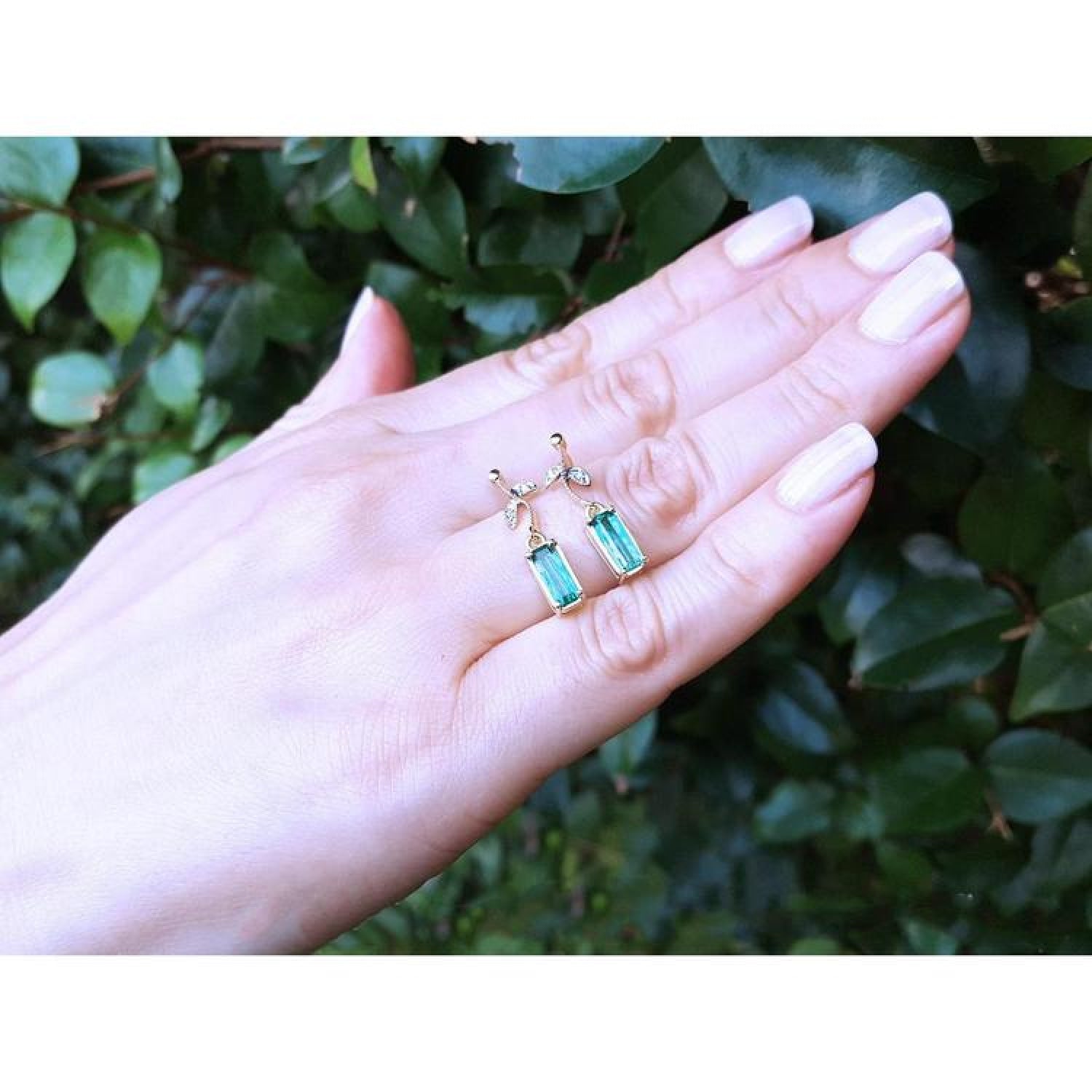 14K gold stud emerald leaf earrings with vibrant rectangular green emeralds and diamonds.