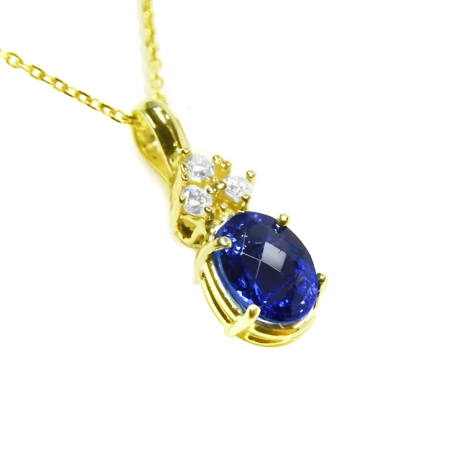 14K yellow gold pendant with a deep blue oval tanzanite and three sparkling diamonds.