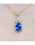 14k yellow gold necklace with a genuine tanzanite and diamonds pendant on a plain background.