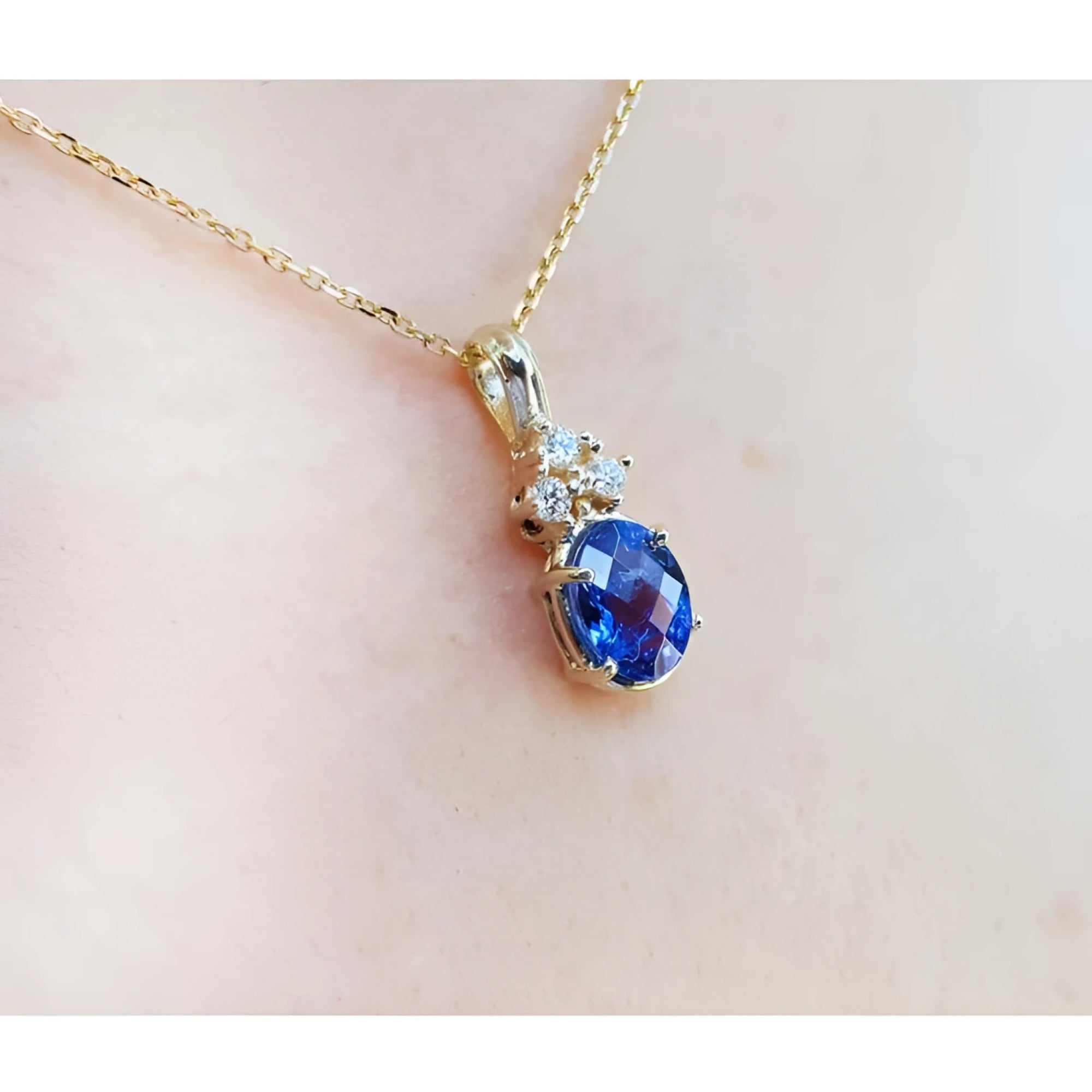 14K yellow gold pendant with oval tanzanite and three diamonds on a delicate chain.