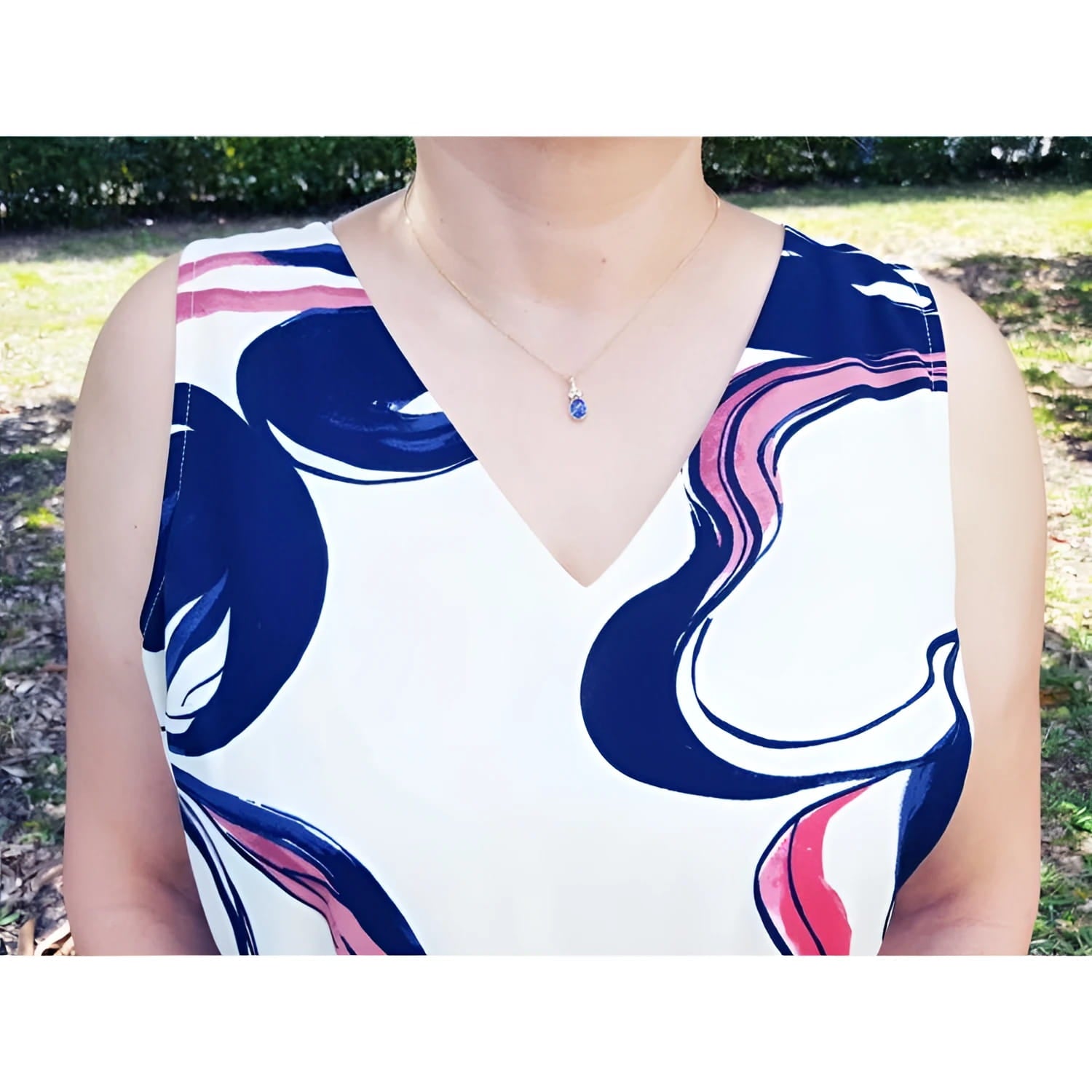 Woman wearing a 14K yellow gold pendant with an oval tanzanite and three diamonds.