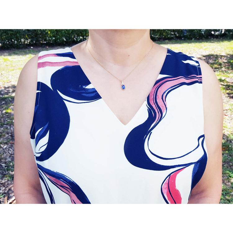 Woman wearing a 14K yellow gold pendant with an oval tanzanite and three diamonds.