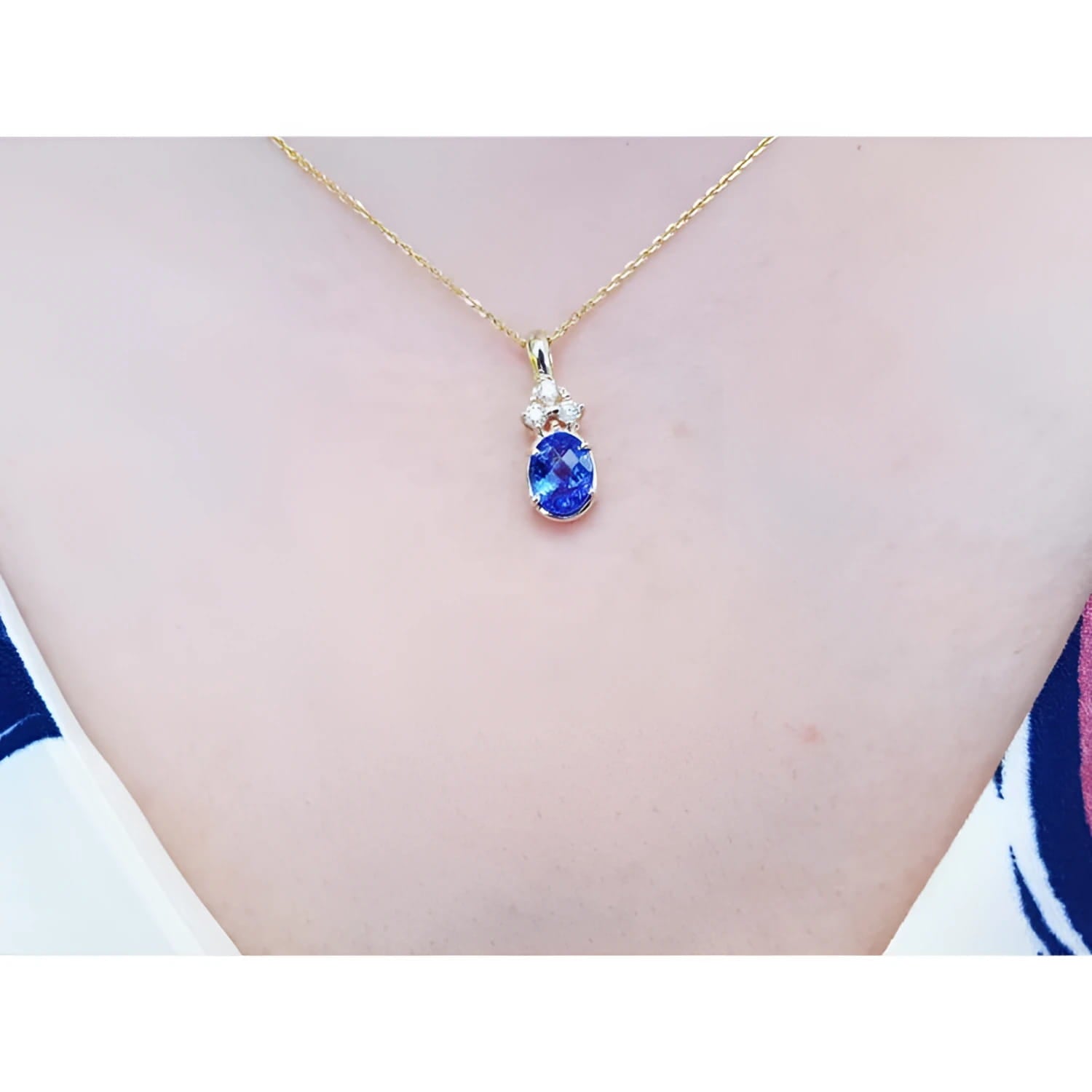 14K yellow gold pendant with an oval tanzanite and three diamonds on a woman's neck.