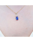 Gold necklace with a natural oval cut tanzanite and diamonds pendant on a person's neck.