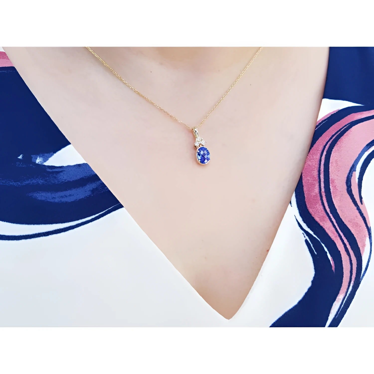 14K yellow gold pendant with oval tanzanite and three diamonds on a woman's neck.