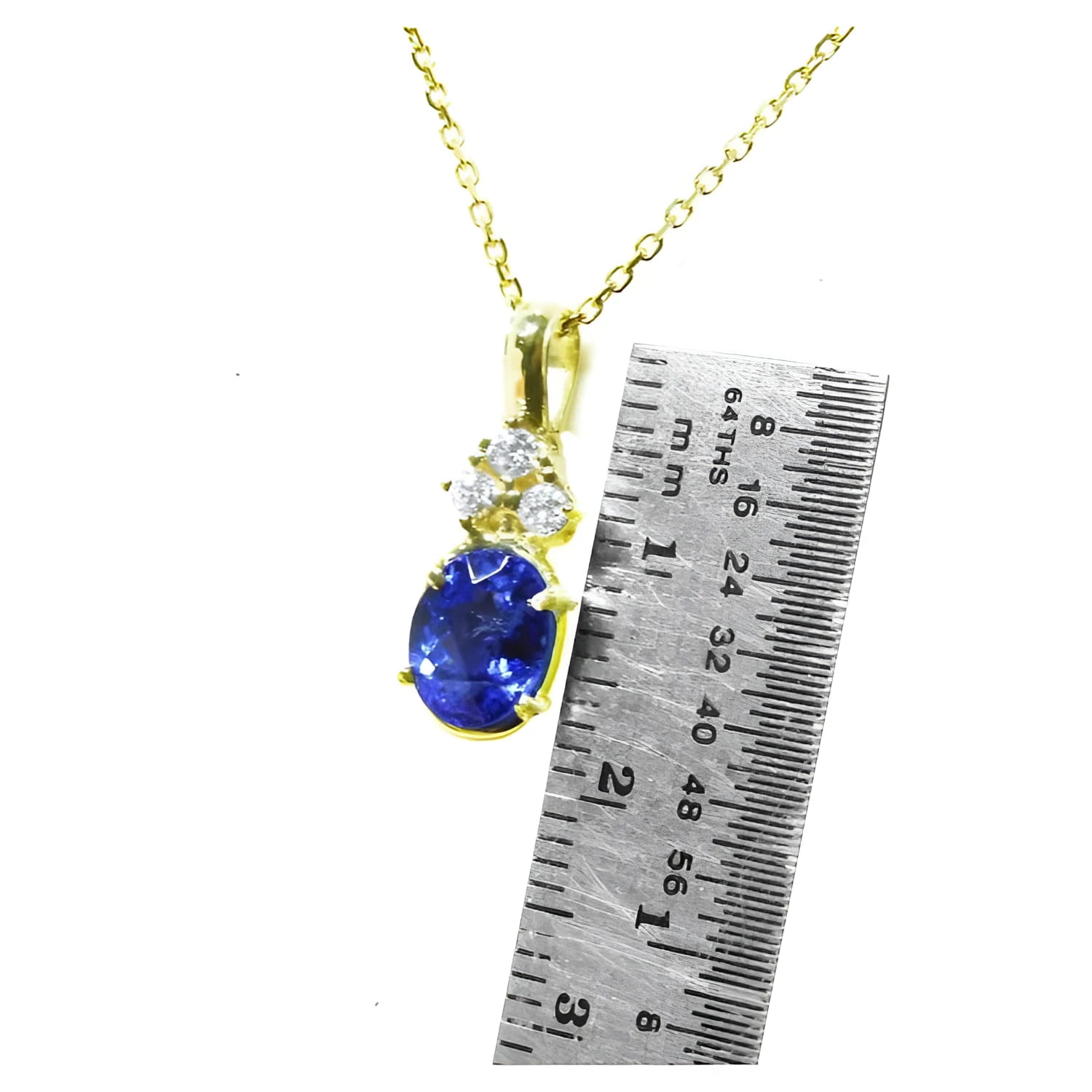 14K yellow gold tanzanite pendant with three diamonds, next to a ruler.