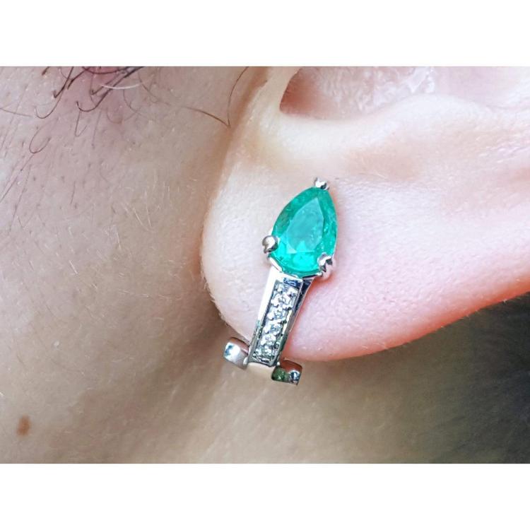 Pear-shaped emerald clip-on earring with accent diamonds in 14K white gold on an ear.