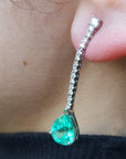 Close-up of a green teardrop earring worn on an ear.