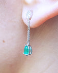 Close-up of a pear shaped dangle earrings worn on an ear.