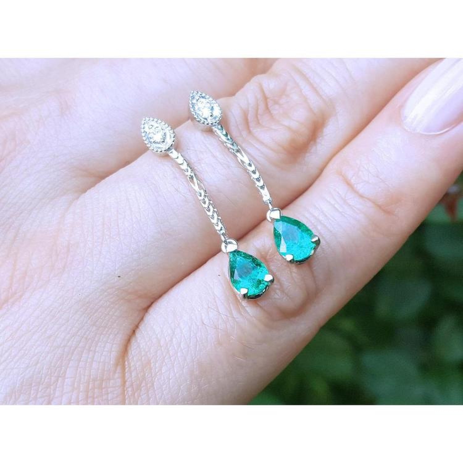 Pear-shaped Muzo Colombian emerald dangle earrings in 14K white gold with diamond accents.