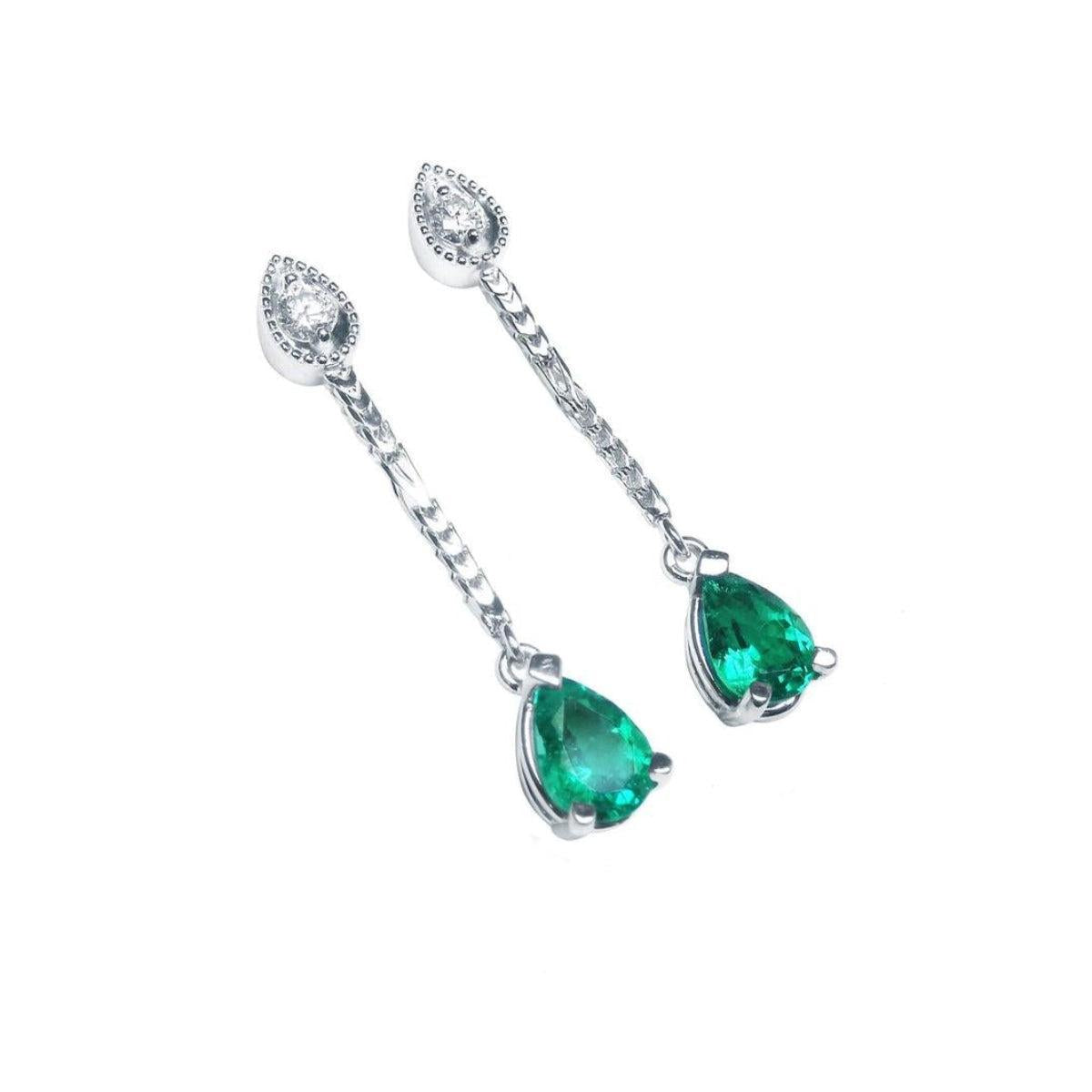 Pair of teardrop emerald dangle earrings on a right-side position top view.