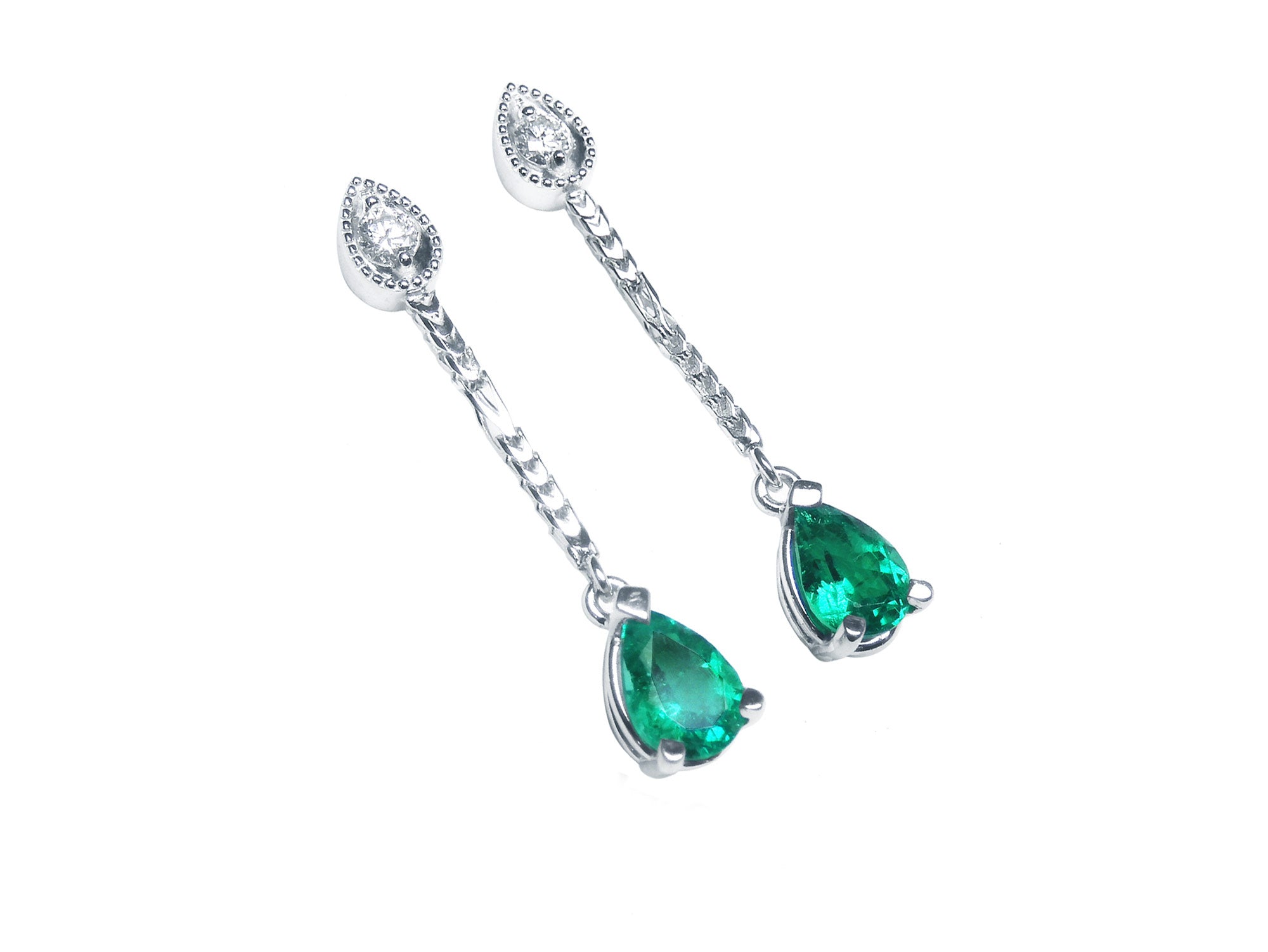 Pair of teardrop emerald dangle earrings on a right-side position top view.