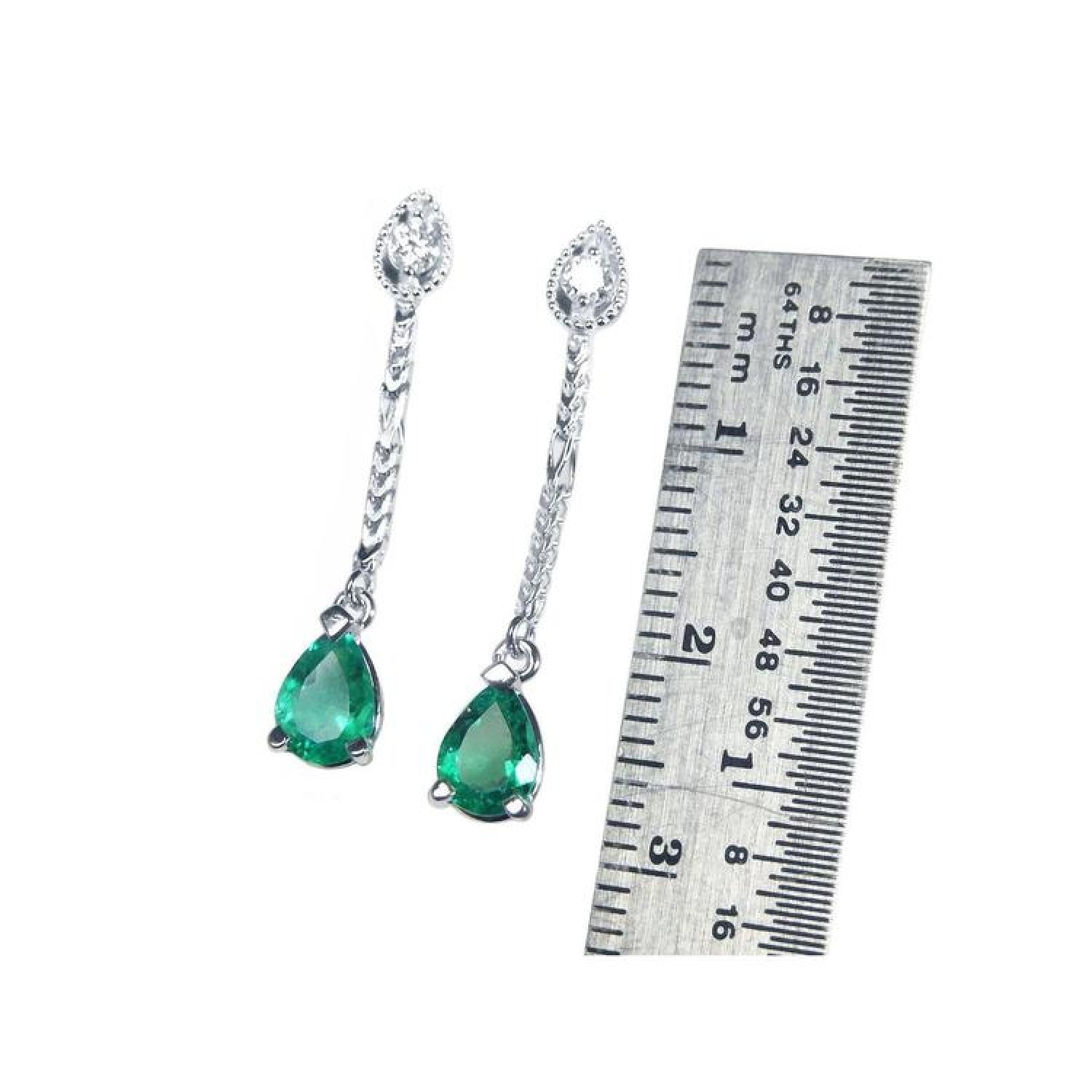 Pear-shaped Muzo Colombian emerald dangle earrings in 14K white gold with diamonds, next to a ruler.