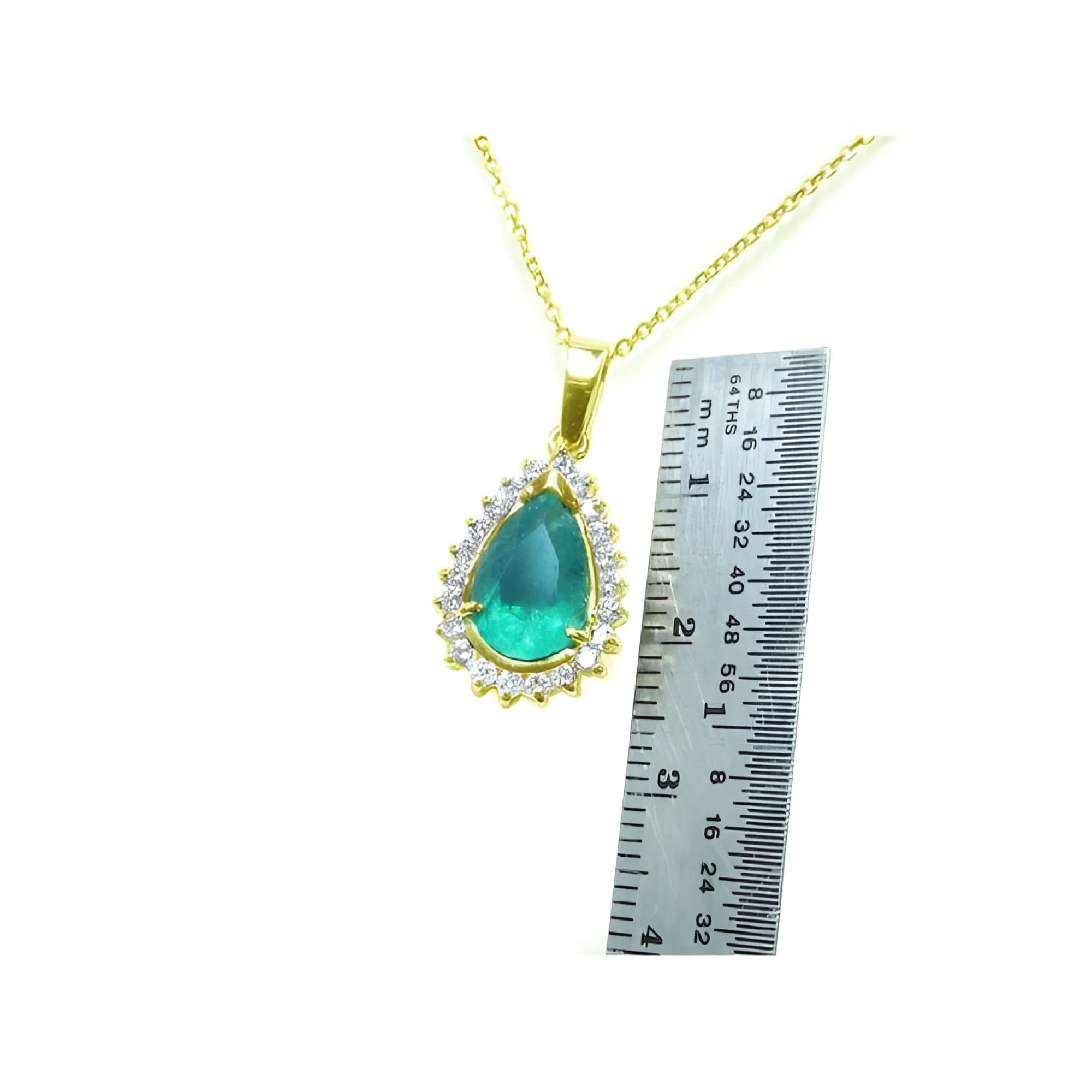 Teardrop Colombian emerald pendant with diamond halo on a gold chain, next to a ruler.