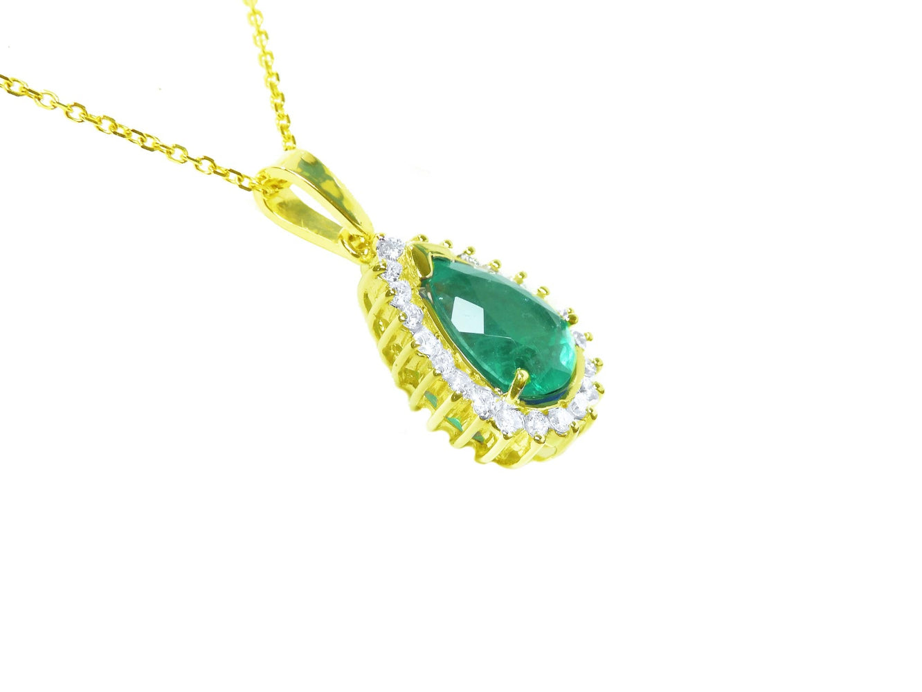A yellow gold necklace with a natural teardrop emerald pendant on a white background