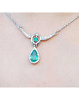 14K white gold necklace with a pear-shaped emerald pendant surrounded by diamonds.