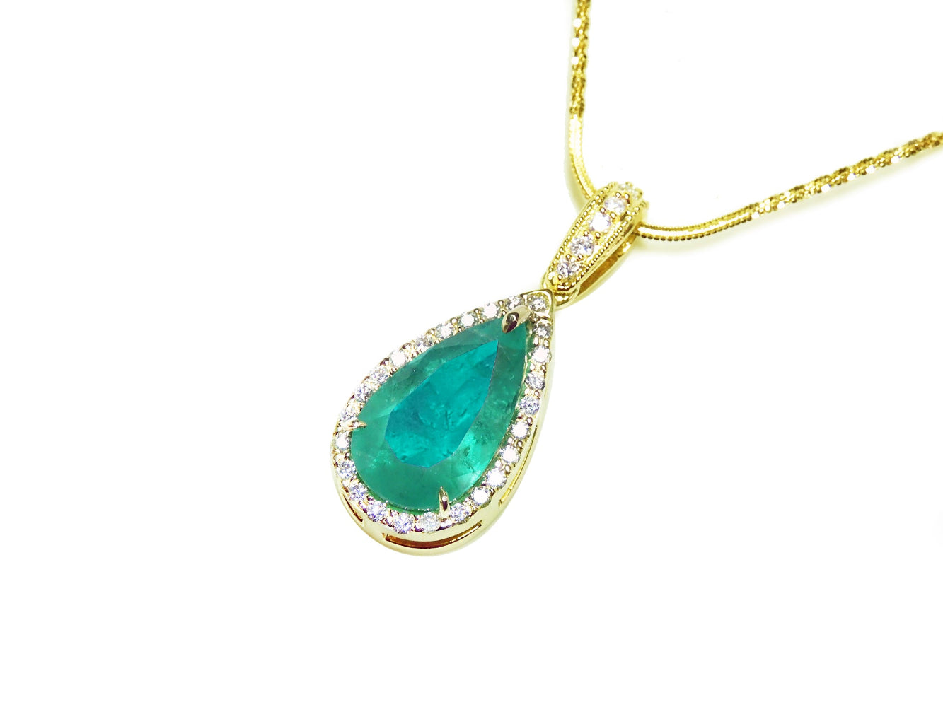 Teardrop-shaped emerald pendant with gold frame and diamond accents on a white background